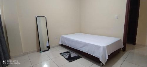 Habitación pequeña con cama con sábana blanca en 2112 en Pereira