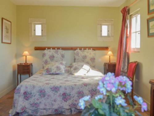 a bedroom with a bed and two lamps and flowers at le Clos in Chambourg-sur-Indre