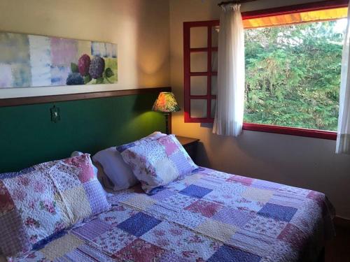 una camera da letto con letto, cuscini e finestra di Pousada Benevento a Campos do Jordão