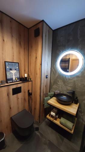 a bathroom with a toilet and a round mirror at Pinewood ANG premium luxurious apartment 15 in Borovets