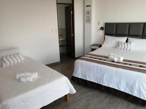 a bedroom with two beds with towels on them at Casa Yuraq Hotel Boutique in Chincha Alta