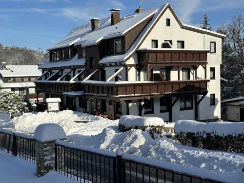 ein großes Haus mit Schnee und einem Zaun in der Unterkunft Hotel Ingeburg in Bad Sachsa