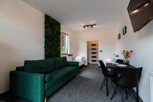 uma sala de estar com um sofá verde e uma mesa em Pokoje Na Winklu em Kluszkowce