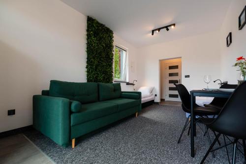 uma sala de estar com um sofá verde e uma mesa em Pokoje Na Winklu em Kluszkowce