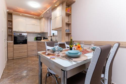 a kitchen with a table with chairs and a bottle of wine at Chic Urban Retreat: Modern 2-Bedroom Gem for Your City Escape in Plovdiv