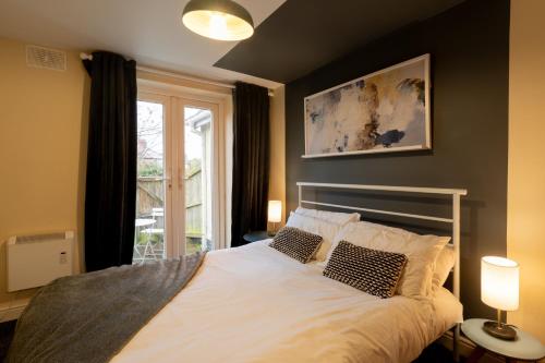 a bedroom with a large white bed with two pillows at Aryas Apartments Oxford - Headington in Oxford