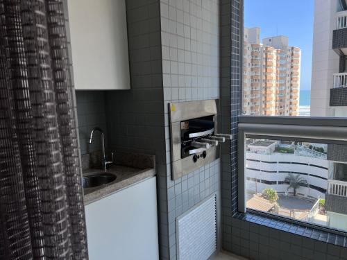 Un baño con lavabo y ventana. en Unitá Praia Grande Boqueirão, en Praia Grande