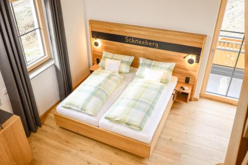 a bedroom with a bed with a wooden headboard and pillows at Höra‘s Apartments Hammerbergblick in Münchberg