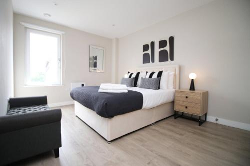 biała sypialnia z dużym łóżkiem i krzesłem w obiekcie 2 BR and Free parking w Cardiff