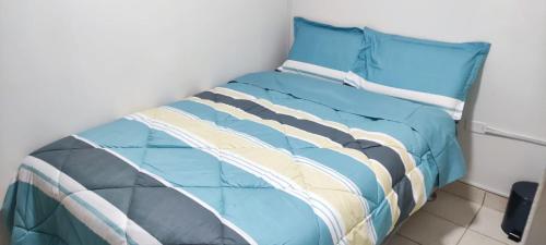 1 cama con edredón azul y almohada en C&B APARTAMENTOS, en Jauja