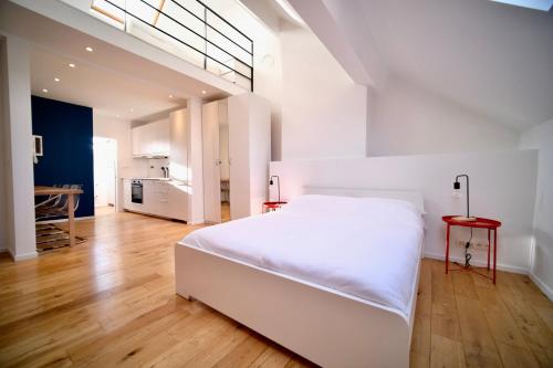 a white bedroom with a white bed and a kitchen at Smart Appart - City Center in Brussels