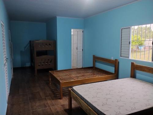 1 dormitorio con 2 camas y pared azul en Chácara Rodrigues, en Piedade