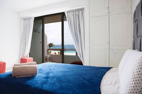 a bedroom with a blue bed with a view of the ocean at Preciosas vista al mar, a 10 min. del aeropuerto -Sol2401- in Cancún