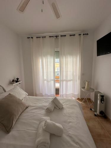 Un dormitorio con una cama blanca con toallas. en Tiyoweh, en Nerja