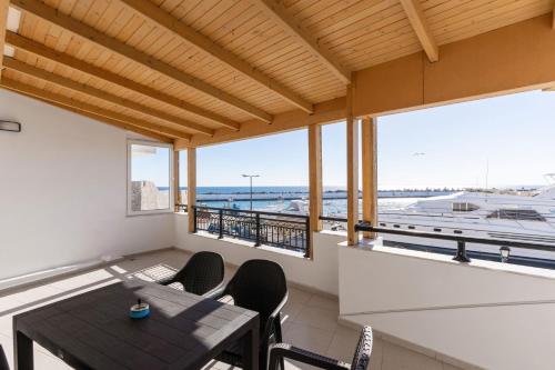 a balcony with a table and chairs and a boat at Port house with amazing sea view and jacuzzi in Ierápetra