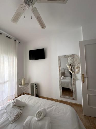 ein weißes Schlafzimmer mit einem Bett und einem Spiegel in der Unterkunft Tiyoweh in Nerja