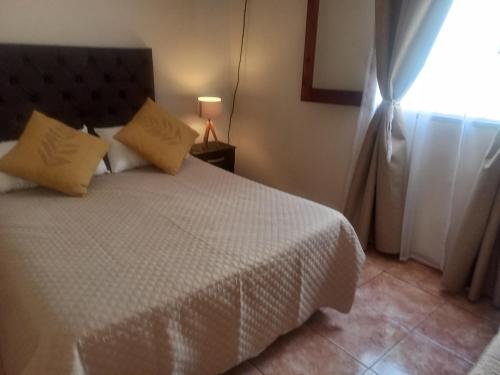 1 dormitorio con cama blanca y ventana en Departamento Montevideana en Villa Mercedes