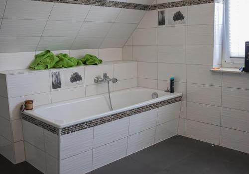 Baño blanco con bañera y toalla verde en Firmen-Familien-Villa, en Heiligengrabe