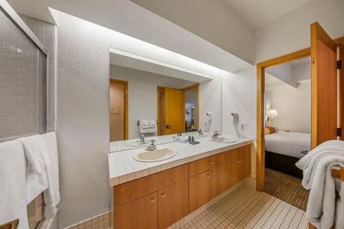 La salle de bains est pourvue de 2 lavabos et d'un grand miroir. dans l'établissement One Bedroom #101, à Olympic Valley