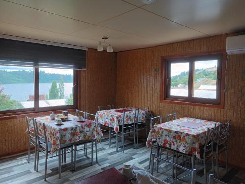 ein Esszimmer mit 2 Tischen, Stühlen und Fenstern in der Unterkunft Casa Chiloe in Rauco