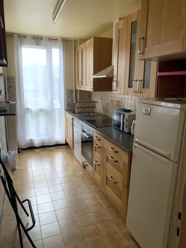 eine Küche mit Holzschränken und einem weißen Kühlschrank in der Unterkunft Appartement chic in Villejuif
