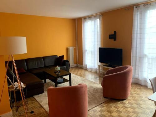 ein Wohnzimmer mit einem Sofa, Stühlen und einem TV in der Unterkunft Appartement chic in Villejuif