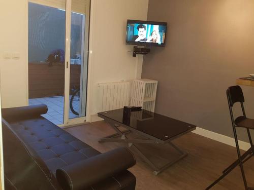 a living room with a couch and a tv on the wall at (Nouvelles literie)ménage gratuit in Bayonne