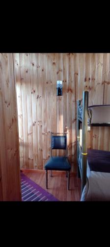 1 dormitorio con silla azul y pared de madera en Alojamiento Las Golondrinas, en San Antonio