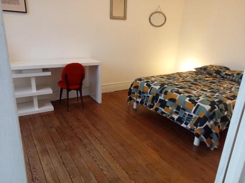 a bedroom with a bed and a desk and a red chair at Grand F2 lumineux in Montceau-les-Mines