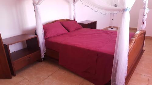 1 dormitorio con cama roja y dosel en Villa CALI SIERRA, en Sambava