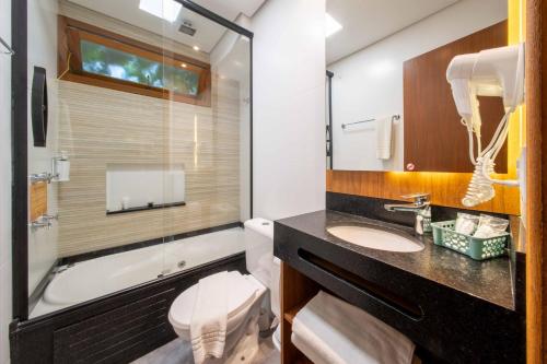 a bathroom with a sink and a tub and a toilet at Bossa Jurerê Hotel in Florianópolis