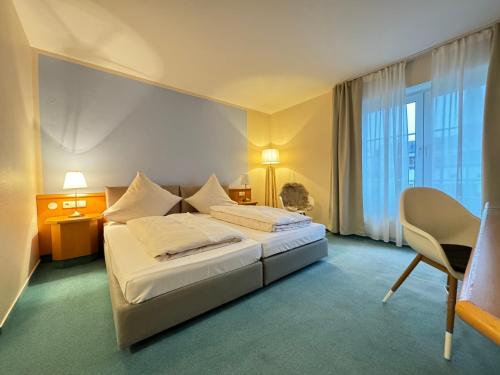 a hotel room with a bed and a desk and a window at Privathotel Bremer in Bergisch Gladbach