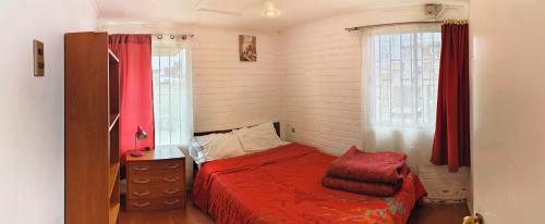 um pequeno quarto com uma cama vermelha e uma janela em Agradable casa al lado de la playa em Las Cruces