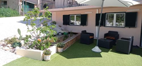 a house with a patio with chairs and an umbrella at La maison du bonheur in Celavisa