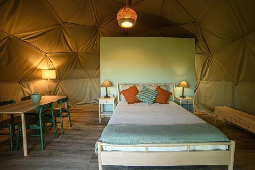 a bedroom in a tent with a bed and a table at Manteiros Glamping in Canas de Senhorim