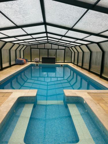 a large swimming pool in a building with a ceiling at Manteiros Glamping in Canas de Senhorim