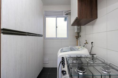 uma pequena cozinha com um lavatório e uma janela em Ap Cloe com piscina próximo ao Aeroporto em Porto Alegre