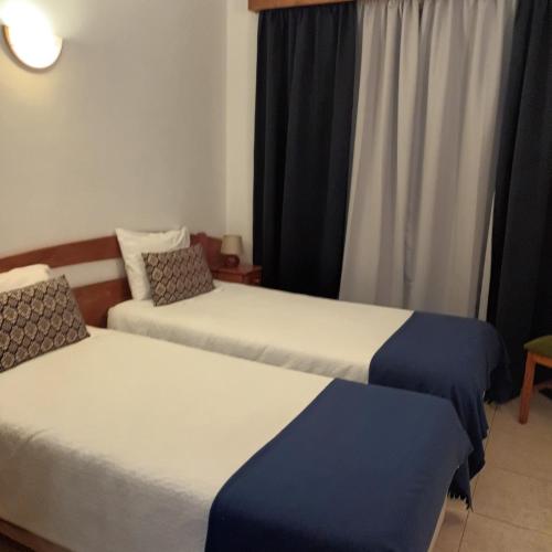 two beds in a room with a window at Hospedaria Descansa Pernas in Monchique