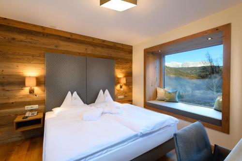 ein Schlafzimmer mit einem großen Bett und einem Fenster in der Unterkunft Gut Berg Naturhotel in St. Johann im Pongau