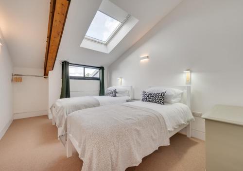Habitación con 3 camas, sábanas blancas y ventana. en No.2 Long Barn, en Wangford