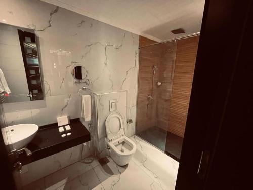 a bathroom with a toilet and a sink and a shower at The Capital Heart Hotel in Baghdād