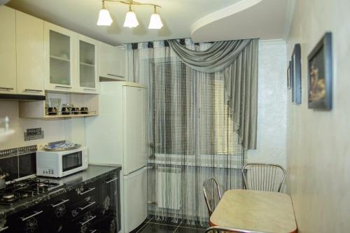 a kitchen with a refrigerator and a table and a microwave at Apartamenty Kharkovskaya in Sumy