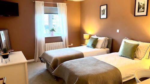 a hotel room with two beds and a window at Riverside View - Large, modern 4 bedroom house with hot tub in Wooler