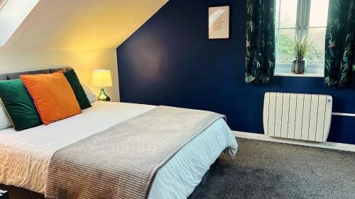 a bedroom with a bed and a blue wall at Riverside View - Large, modern 4 bedroom house with hot tub in Wooler