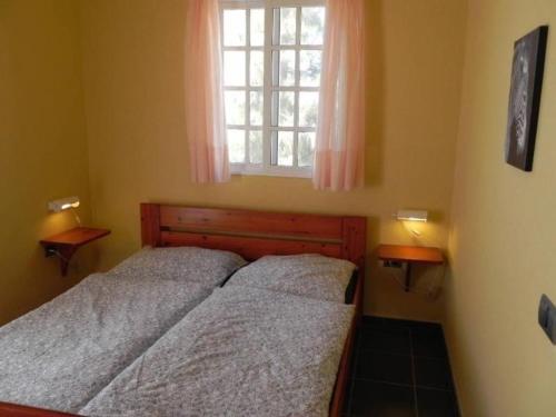 2 camas en un dormitorio pequeño con ventana en Kleiner Bungalow mit einem Schlafzimmer, en Puerto Naos