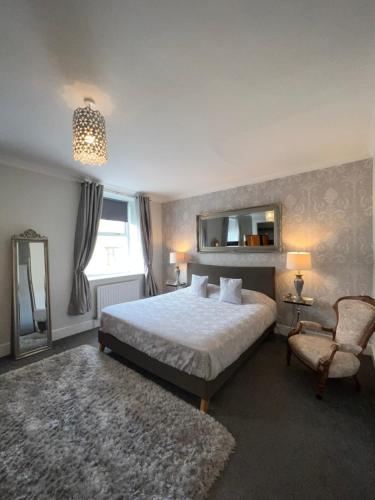 a bedroom with a bed and a mirror and a chair at Tynwald Apartments in Douglas