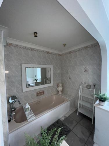 a bathroom with a tub and a sink at Tynwald Apartments in Douglas