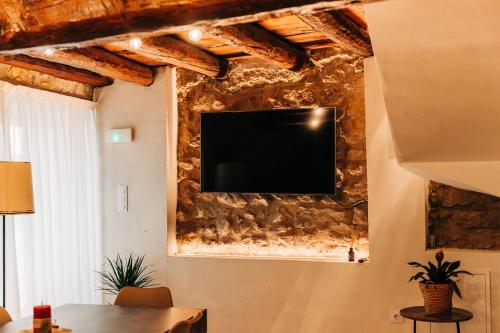 a television on a stone wall in a living room at Casa Pelegrí in Morella