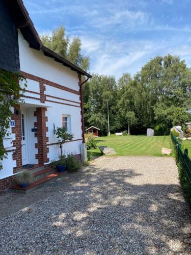 a house with a gravel driveway next to a yard at Landhaus Oscar (150m zum Strand) in Westerholz