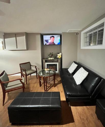 a living room with a black leather couch and a tv at West Edmonton Perle Palace in Edmonton